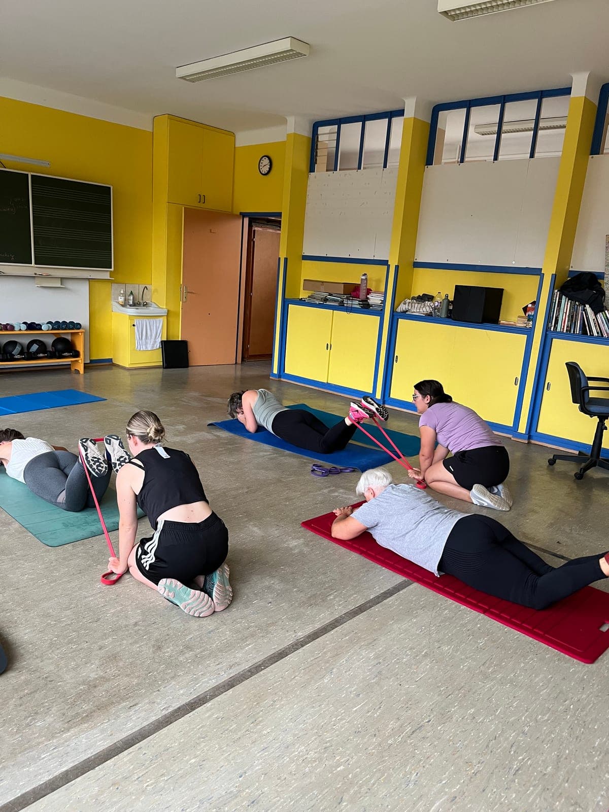 Cours collectif de renforcement musculaire : exercices au sol avec élastiques, encadrés par Célia